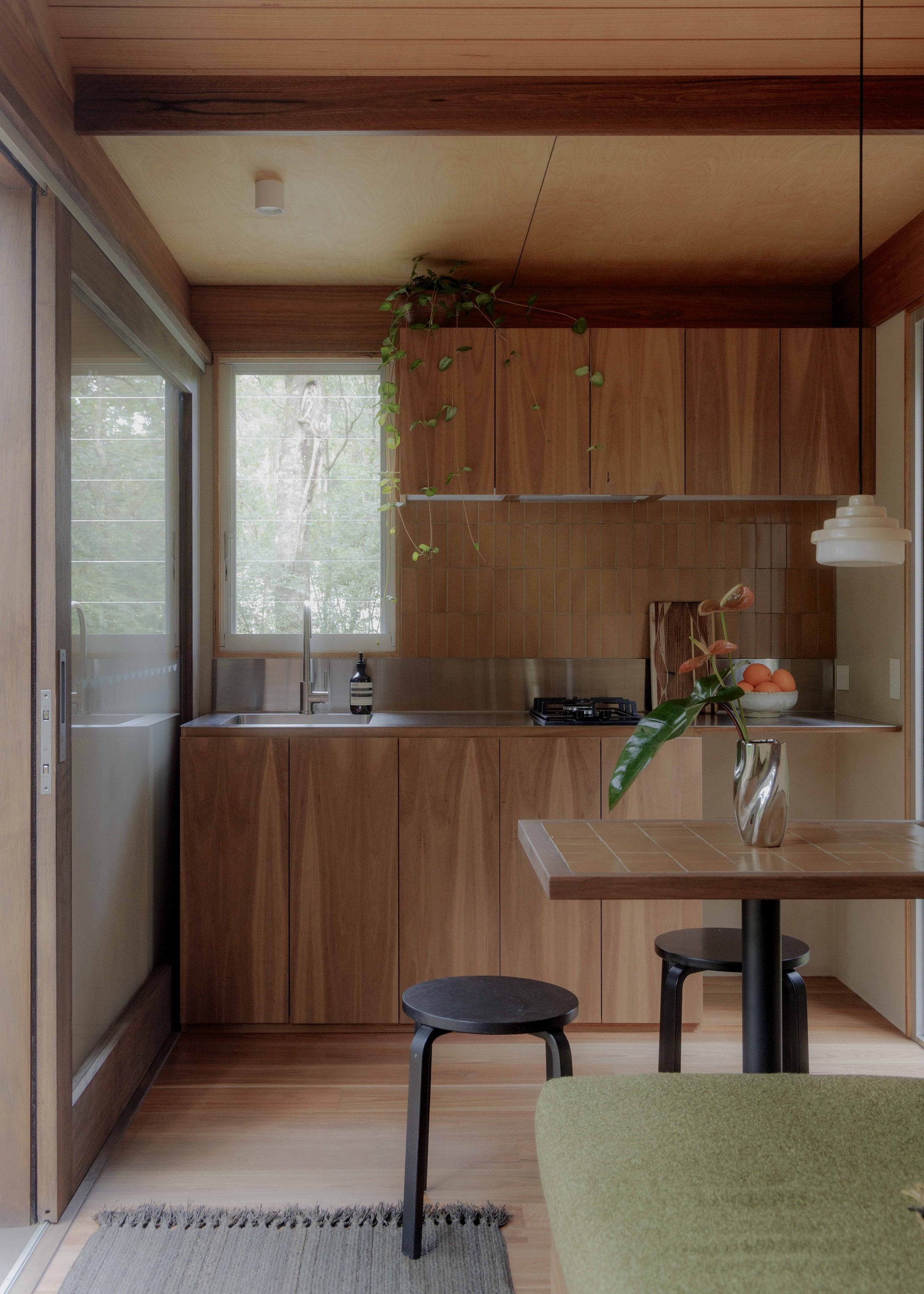 Kitchen and dining area with timber cabinetry, tiled splashback and integrated sofa