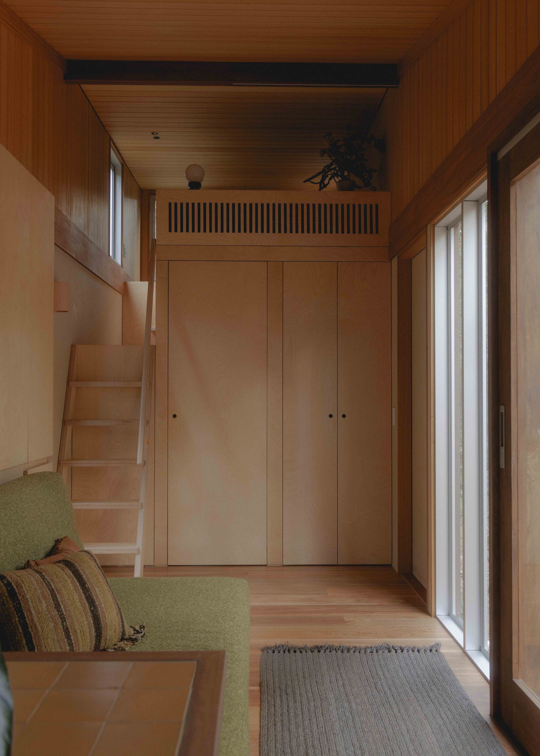 Living area with integrated green sofa and ladder to loft